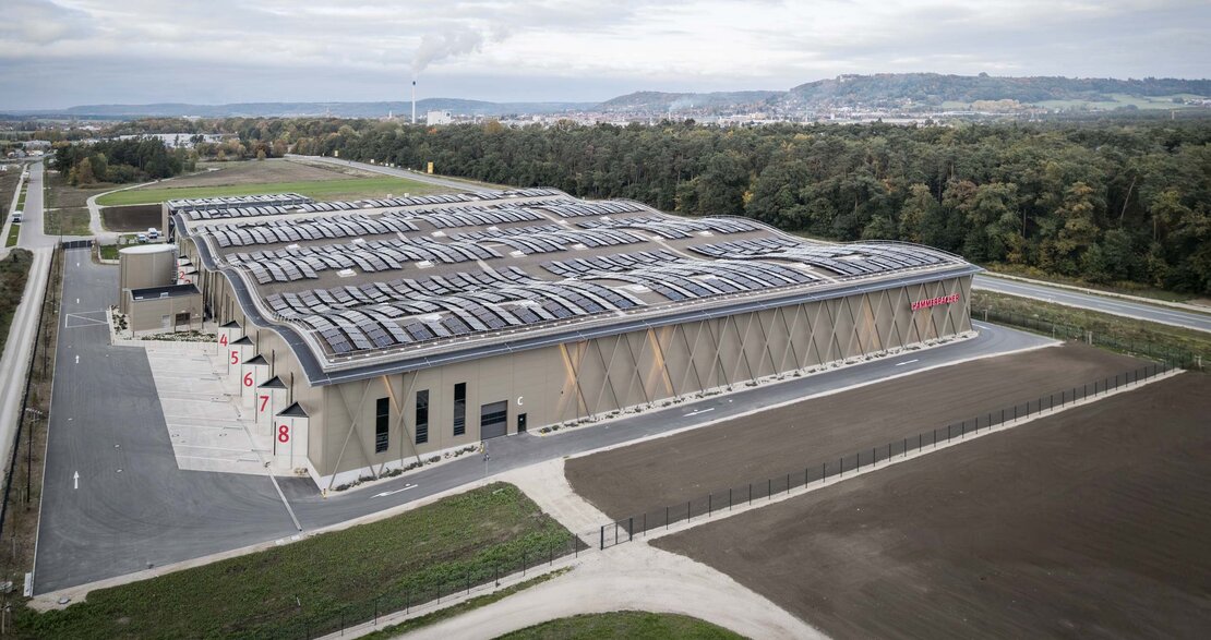 Luftaufnahme Logistikzentrum Neumarkt in der Oberpfalz mit Roma MiWo-Sandwichfassade Typ FV eco im Farbton ähnlich RAL 1035 perlbeige und Dach mit PV-Modulen
