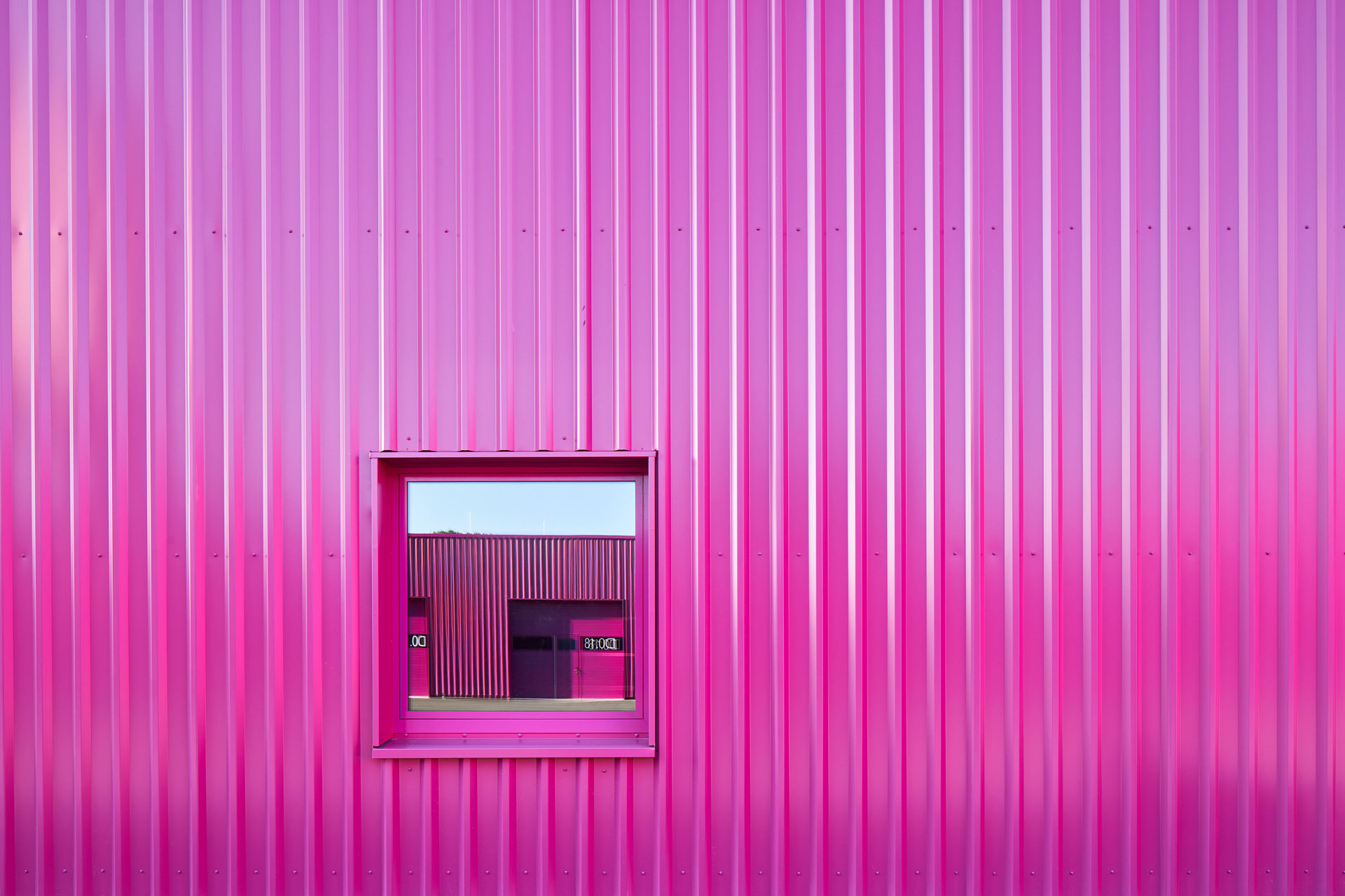 Monochrome Fassadenfläche des Werkhofes mit bündig eingesetztem Fenster und farbtreuer Einfassung