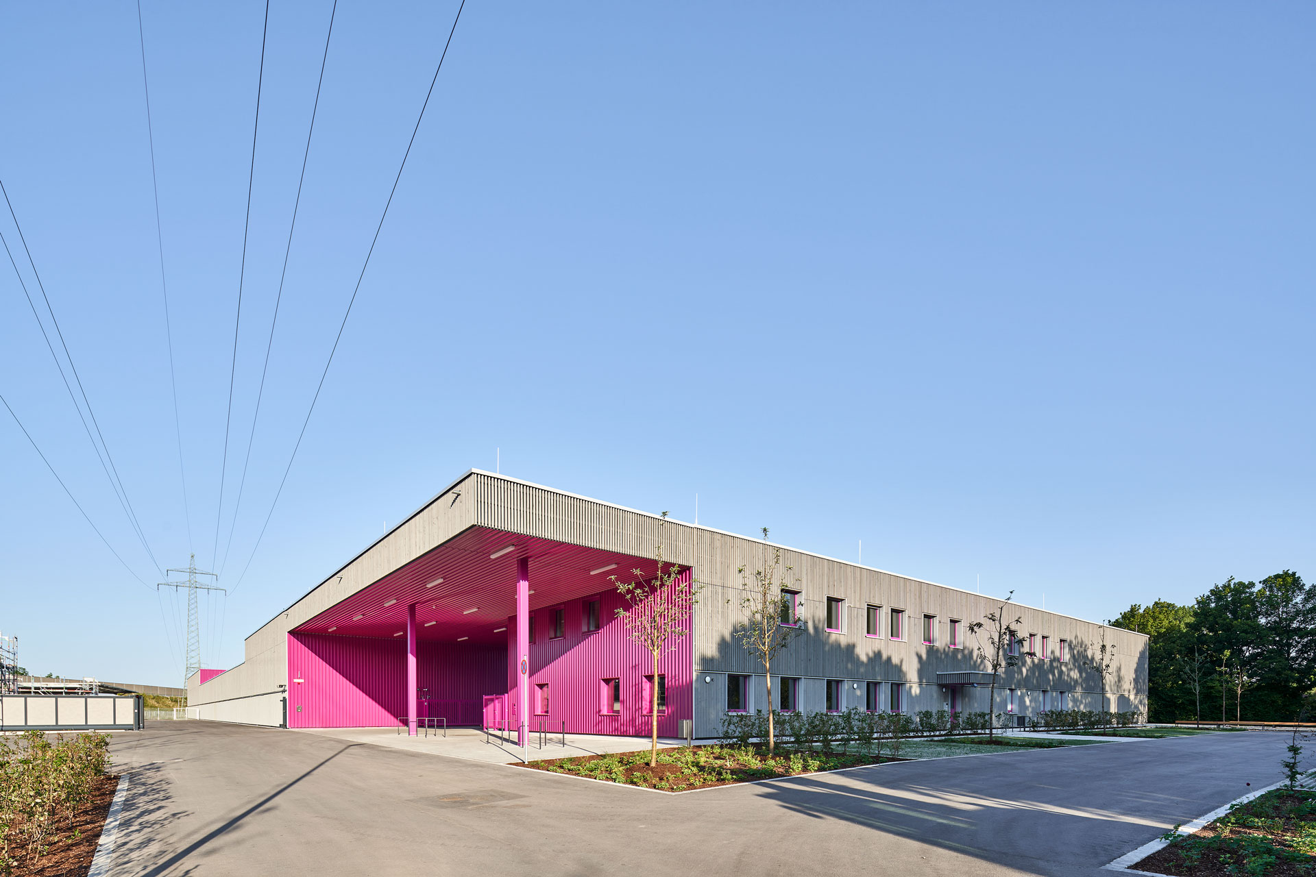 Bauhof in Weitwinkelansicht mit großformatiger Toröffnung, purpurfarbener Eingangsggestaltung und anschließendem Verwaltungsbau