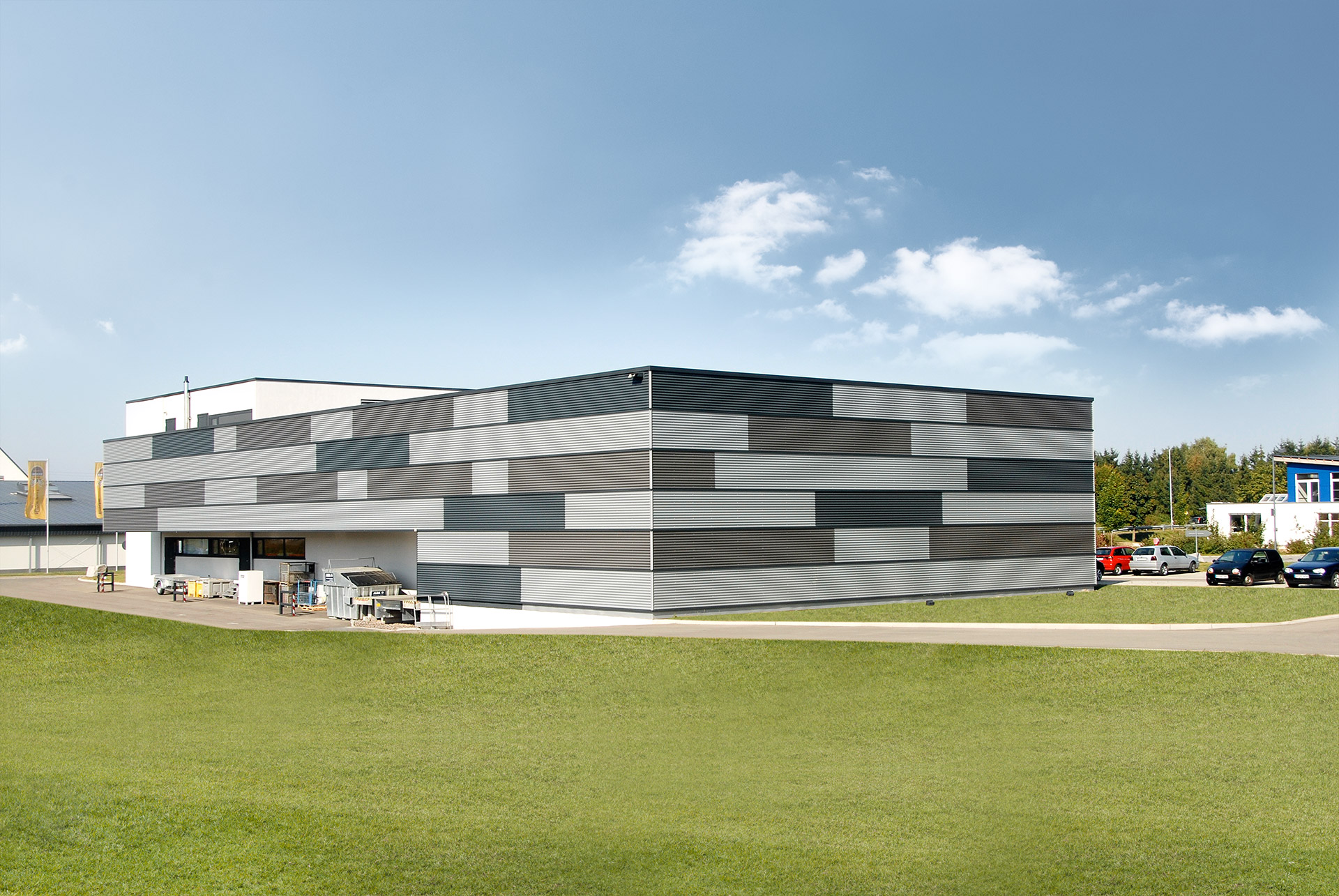 Gesamtansicht der mehrfarbigen Wellprofilfassade der Produktionshalle